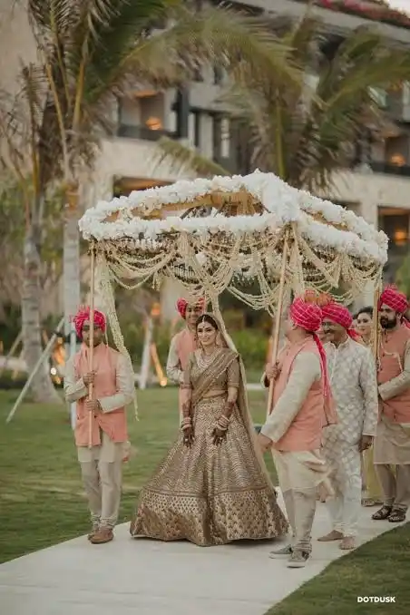 Bride walking under a reworked phoolon ki chaadar flower canopy entry