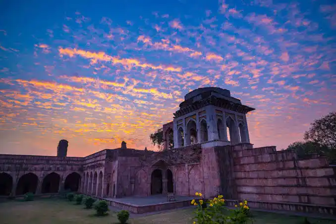 Historic architecture of Mandu in Madhya Pradesh under a colorful sunset sky.