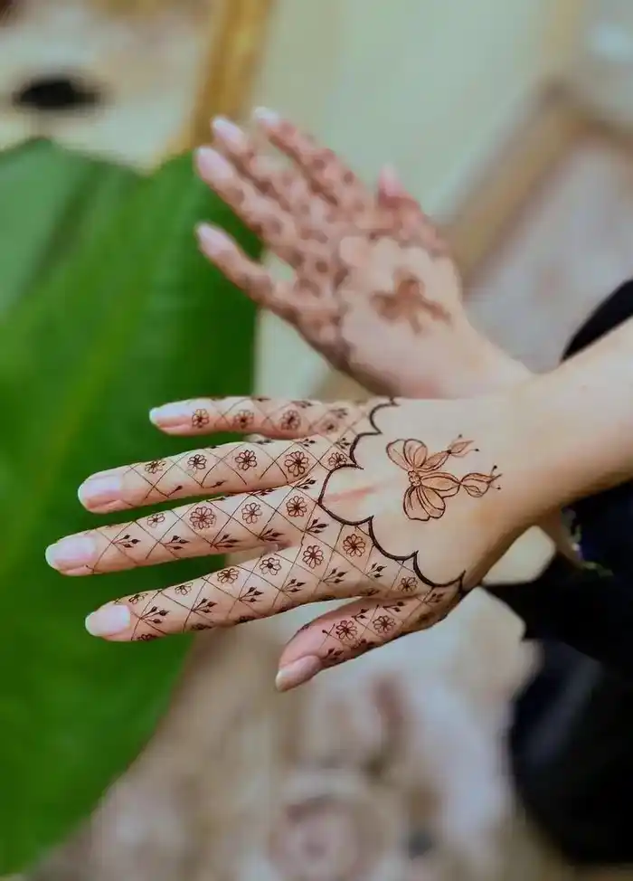 a khafif mehndi design close-up: fine lines, small florals, visible negative space, on the back of the hand